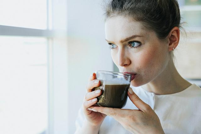 Kvinde drikker kaffe idet hun finder sin nye favoritkaffe på arbejdspladsen